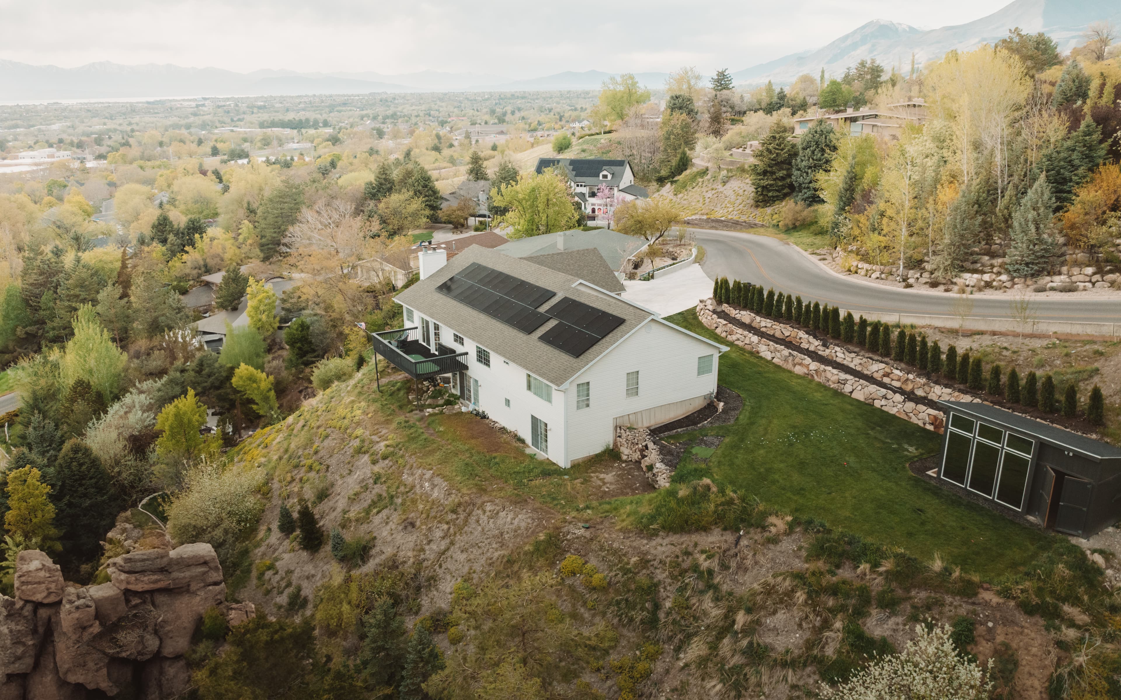 Aerial view of suburban home with solar panels on roof, bright sunny day
