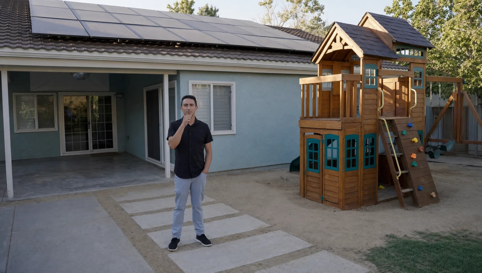 Homeowner standing outside a solar-powered home in the backyard